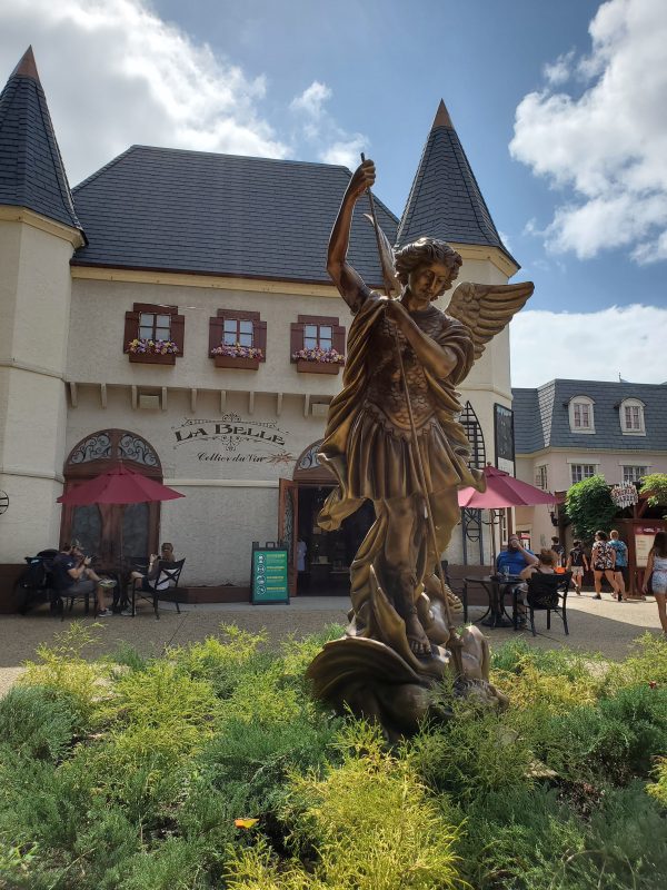 An angel statue with a French-style village in the background