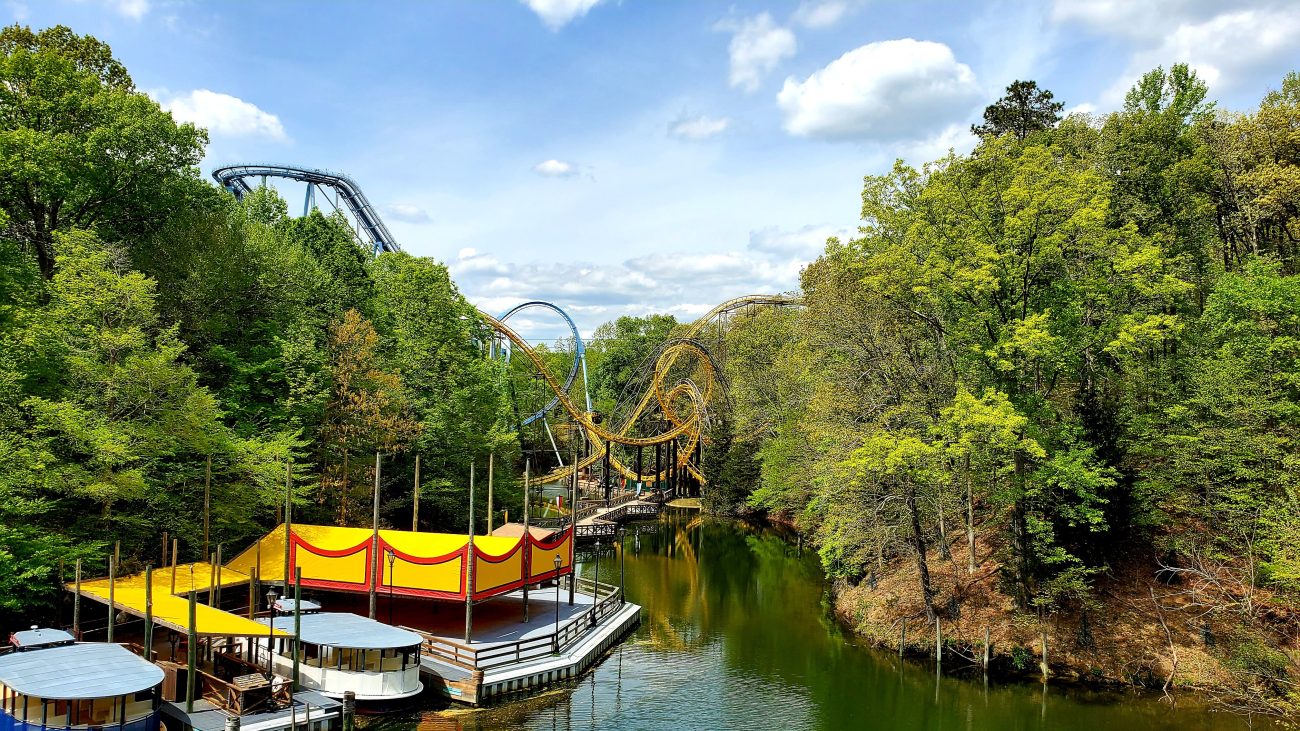 2 roller coasters set on a river with trees and blue sky in teh background at busch gardens williamsburg