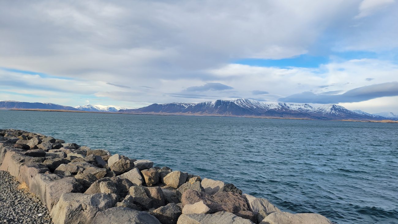 Reykjavik harbor on a sunny day with mountains in the distance