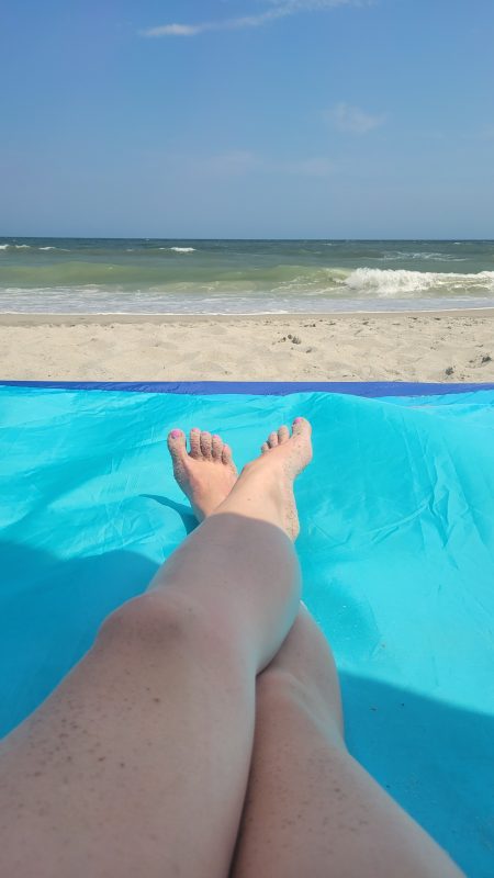 Feet on a beach mat with the ocean in the background